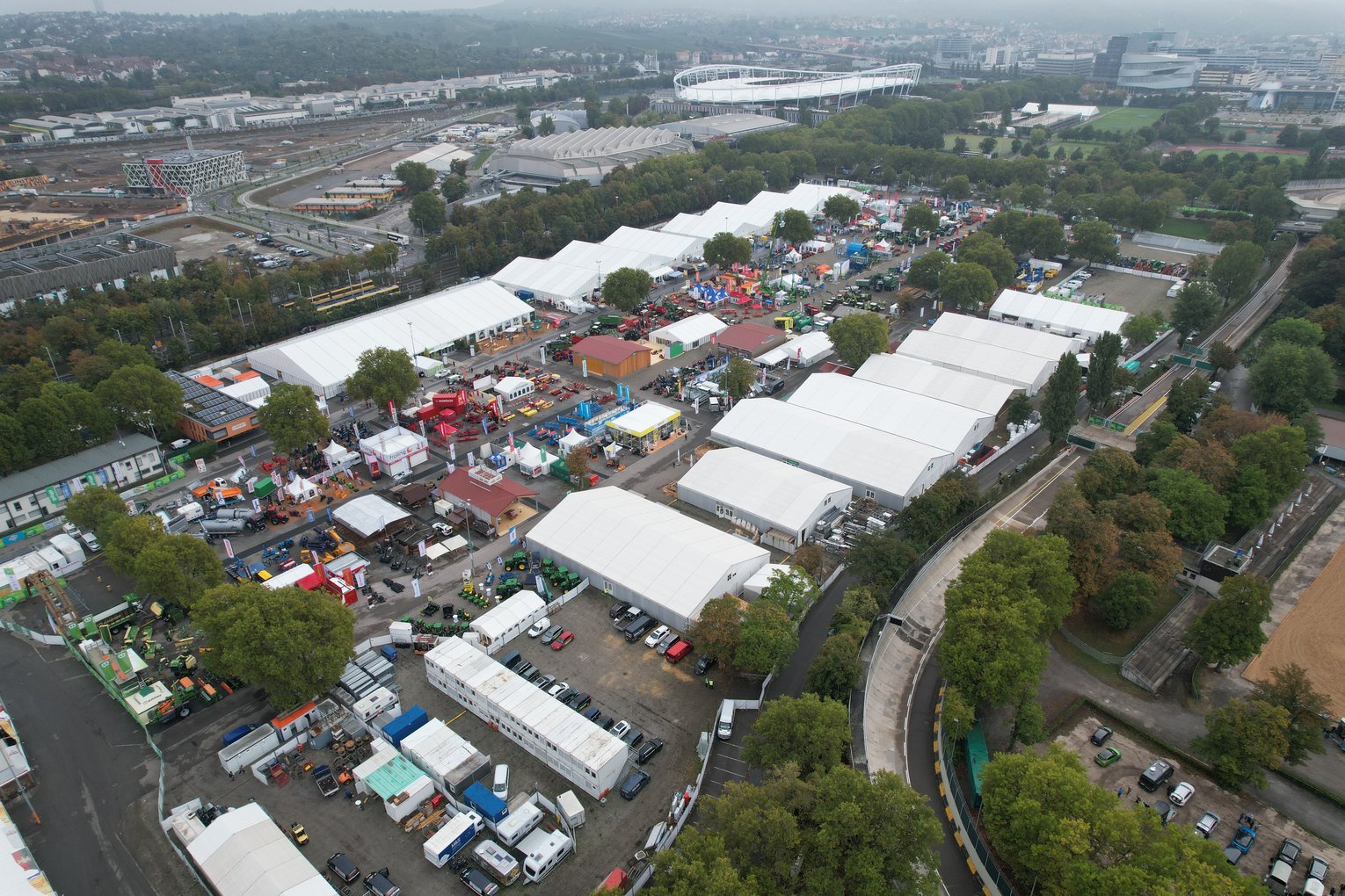 Luftaufnahme des Geländes des Landwirtschaftlichen Hauptfests 2022 mit mehreren Messezelten und Ausstellern, umgeben von Straßen, Bäumen und Gebäuden.