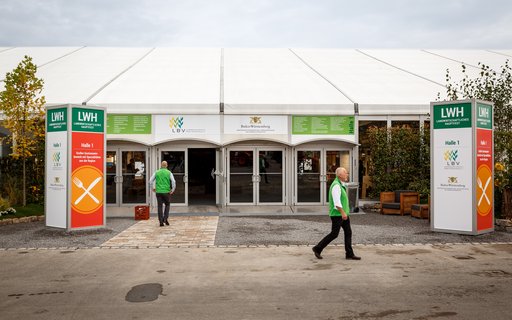Eingang eines großen, weißen Zelts mit der Beschriftung „Halle 1“ sowie den Logos des Landesbauernverband in Baden-Württemberg e. V. und des Ministeriums für Ernährung, Ländlichen Raum und Verbraucherschutz Baden-Württemberg. 